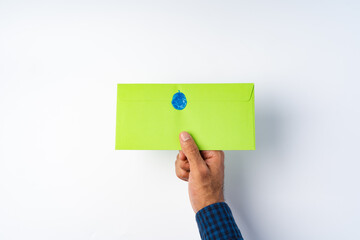 Male hand holding closed envelope above the white surface