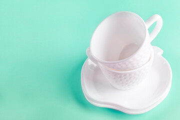 Two beautiful white cups (mugs) in the shape of strawberries and two saucers stacked on top of each other on a green background. Space for text. Empty clean dishes.