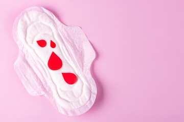 Women's Menstrual pads (sanitary napkin) with red drops on a pink background. The concept of critical days, PMS, menstruation. Space for text.
