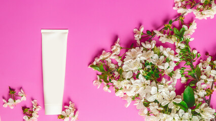 Cosmetic cream tube packaging on pink background. Beauty, skincare and natural cosmetics concept. Mockup for design. Top view, flat lay. Womens day, mother day