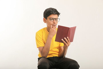 Indian boy holding diary in hand and thinking some idea on white background.