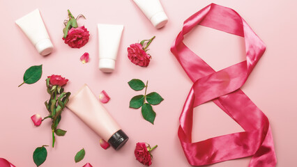 Set of skin care products on pink pastel background with roses flowers. Skin care concept.