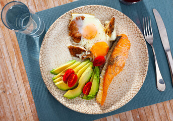 Healthy dinner, grilled salmon fillet with ripe avocado, cherry tomatoes and fried egg