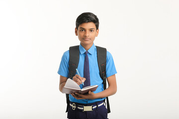 Indian school boy in uniform and holding diary in hand on white background.