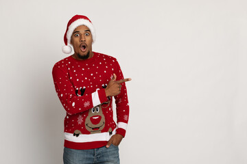 Shocked black man in Santa hat pointing at copy space