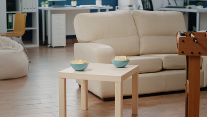 Close up of chips on table in empty business office to drink with colleagues after work. Nobody in workplace with foosball game table to do fun activity with snacks to celebrate party