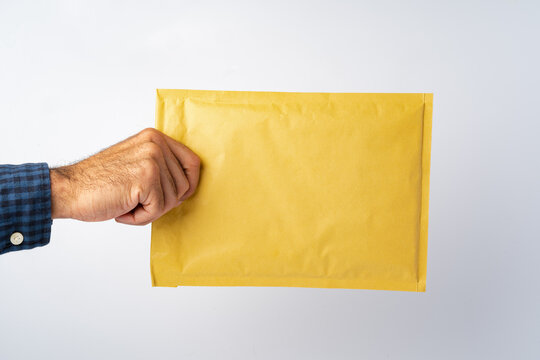 Male hand holding parcel post against white background