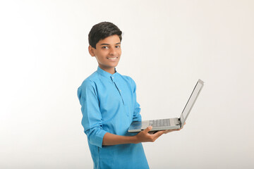 Technology concept : Cute indian little school boy using laptop