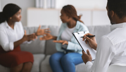 Black LGBT couple having session with male psychologist at office, selective focus. Copy space