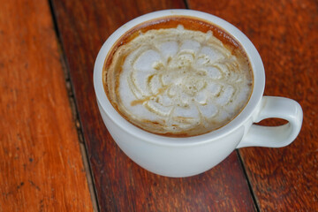 closeup hot caramel macchiato coffee in white ceramic cup on a wooden floor background, food, drink, copy space
