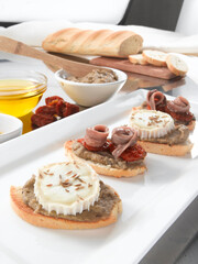 Canapés de queso y anchoas sobre pan. Canapes of cheese and anchovies on bread.