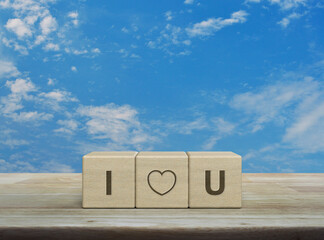 I love you letter on wood block cubes on wooden table over blue sky with white clouds, Valentines day concept