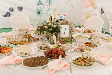 Beautifully decorated catering banquet table with different food snacks and appetizers with sandwich, caviar, fresh fruits on corporate party event or wedding celebration