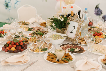 Beautifully decorated catering banquet table with different food snacks and appetizers with sandwich, caviar, fresh fruits on corporate party event or wedding celebration