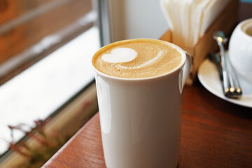 Hot cappuccino with a beautiful foam in a white mug on the table. Beautiful coffee serving. Freshly brewed cappuccino with vegetable milk with beautiful latte art