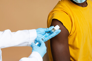 Unrecognizable Doctor Wearing Blue Medical Gloves Making Vaccination To Black Male Patient