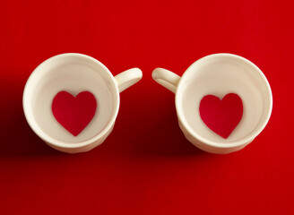 Two cups of coffee with hearts on red background. Flat lay, top view	