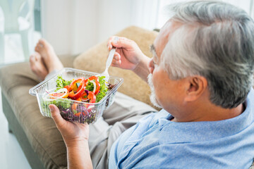 Mature man with pumpkin and healthy food, Portrait Asian Senior man eating a salad in house, Old...