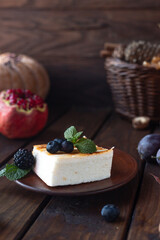 A square piece of cottage cheese casserole lies on a plate, decorated with berries and mint leaves