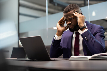 Concentrated black businessman solving business tasks, using computer