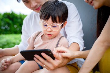 little kid boy using digital tablet or smart phones for playing games and watching cartoons with dad and mom, smart phone mobile addiction technology communication lifestyles.
