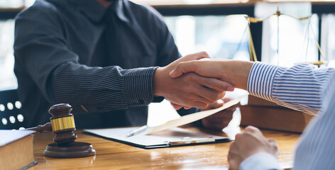 Businessmen shaking hands above the wooden desk in a modern office, close up. Unknown business people at meeting. Teamwork, partnership and handshake concept.