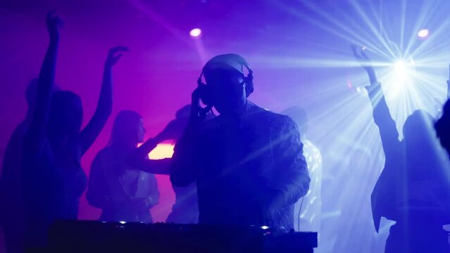 Attractive young women dancing in club around DJ. Nightlife, modern music and entertainment concept.