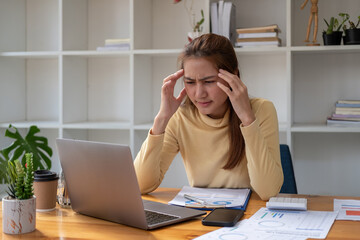 Working woman have a headache, Young Asian businesswoman working on a laptop and paperwork is stressed has a headache and thinks hard at the office