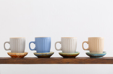 colorful cups on  wooden shelf on  white background