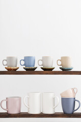 colorful cups on  wooden shelf on  white background