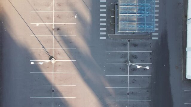 Aerial view empty grocery store parking lot with white car driving by