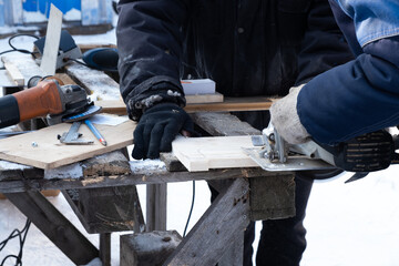 Two a worker in a protective suit treats a wood with a power tool