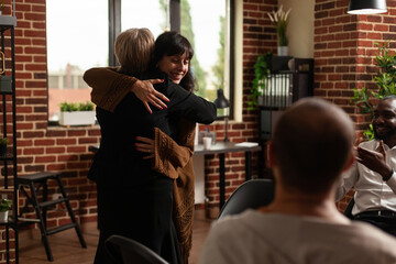 Woman and therapist hugging after sharing recovery progress with aa meeting group. Psychotherapist...