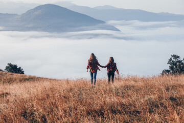 Naklejka premium Two Girls in Red Plaid Shirts Walking in the Mountains