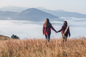 Two Girls in Red Plaid Shirts Walking in the Mountains