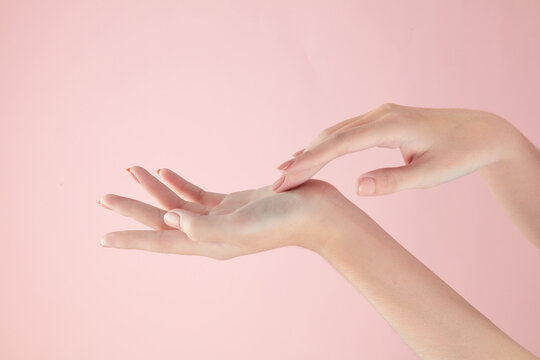 Hand model using a cosmetic with a pink background for cosmetic advertising
