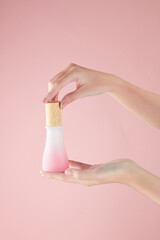 Hand model holding a cosmetic jar with a pink background for cosmetic advertising