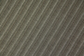 The texture of the costume fabric, diagonal pattern, neutral color. diagonal fabric background, material. Striped texture. Coarse woolen fabric with a black-white-brown pinstripe print.