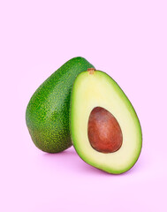 avocado cut in half on a light pink background	
