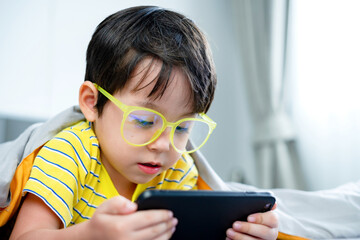 little kid boy using digital tablet or smart phones for playing games and watching cartoons, smart phone mobile addiction technology communication lifestyles.