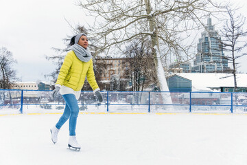 Young african american woman skating on the ice rink