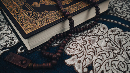 close up holy quran on a prayer matt with prayer beads for background