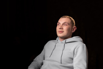 Portrait of a young man with a mutilated eye. Dark background. The young man looks away. Eye injury, recovery after surgery.