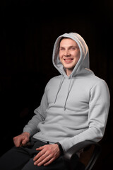 Portrait of a smiling young man with a mutilated eye. Dark background. A young man looks into the camera. Eye injury, recovery after surgery. Happy face.