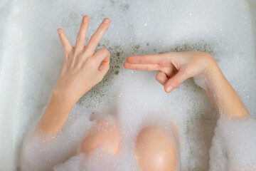 Masturbation, sex in the bath concept. Female hands in a bath with foam depict erotic gestures. Sexual gratification in the bath.