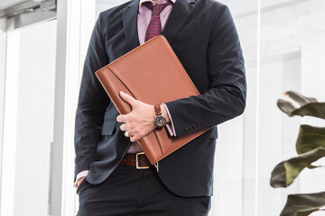Brown leather business padfolio portfolio folder held by man in business suit