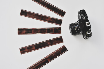 Top view of vintage analog film camera and 35mm film negatives in protective sleeves.