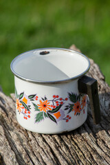 antique white enamelled steel pot decorated with flower patterns. space copy. selective approach.