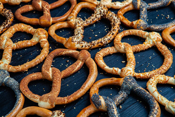 Fresh prepared homemade soft pretzels. Different types of baked bagels with seeds on a black background.