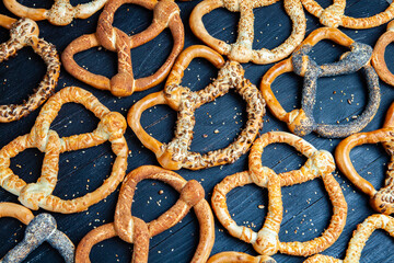 Fresh prepared homemade soft pretzels. Different types of baked bagels with seeds on a black background.